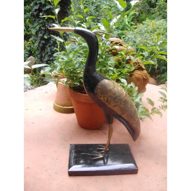 A sculpture, I believe a stylized grey heron, crafted using an impressive marble mosaic technique. The beak has been...