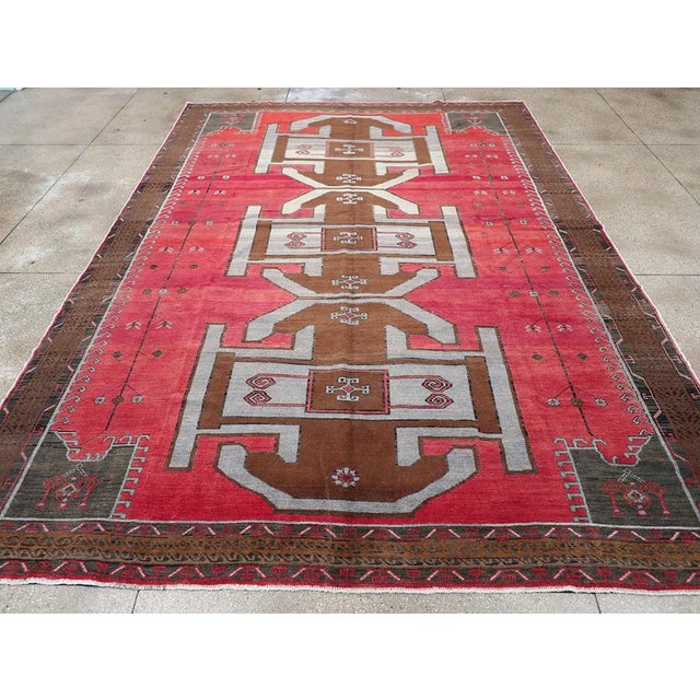 A wool pile of symmetric knots on a cotton foundation. This village piece shows its Kazak sources with a soft salmon-rose...