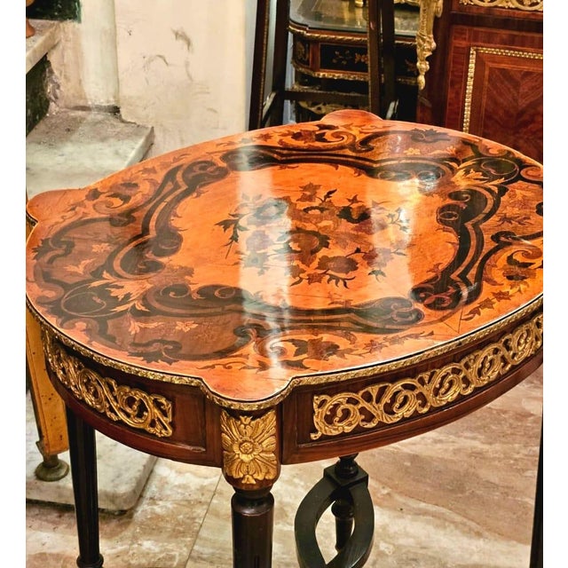 Elegant French style wood side table featuring a sophisticated glass top that beautifully showcases the decorative artwork...