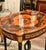 Elegant French style wood side table featuring a sophisticated glass top that beautifully showcases the decorative artwork...