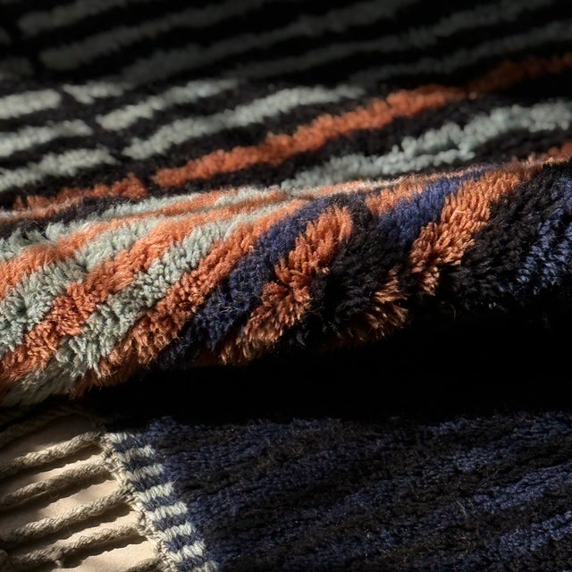 A rug of clean, architectural lines — deep vertical stripes shift from midnight black to a slim rust accent to soft ivory,...