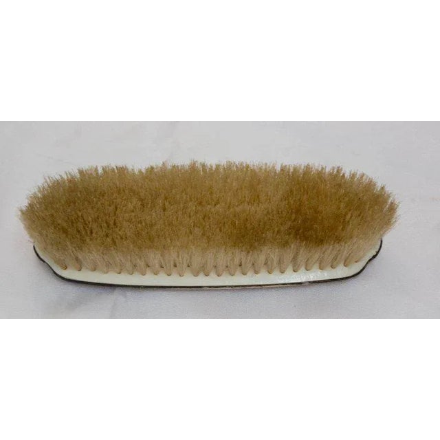 A lovely garland of flowers surrounded by a swirled border decorate the sterling silver of this Victorian clothes brush....