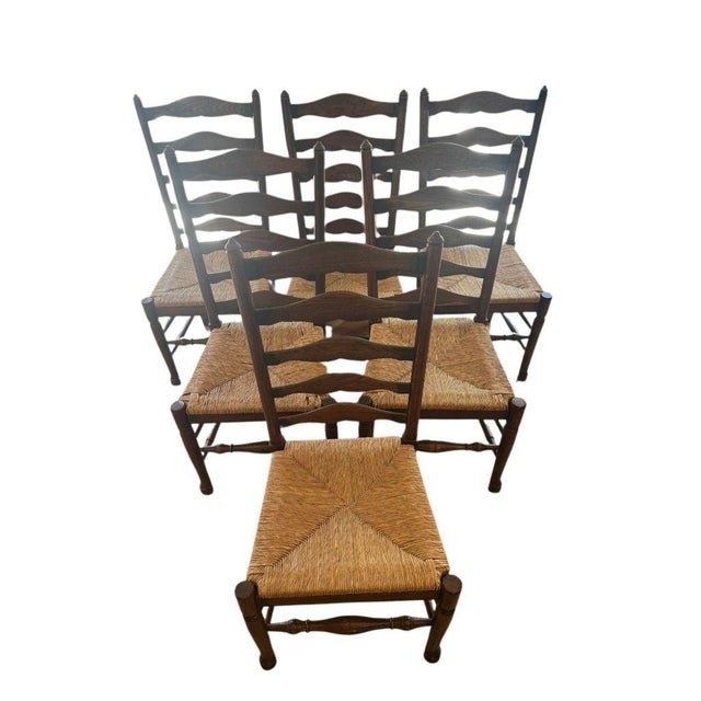 Classic set of six vintage ladderback dining chairs with original woven rush seats. Featuring timeless slat-back...
