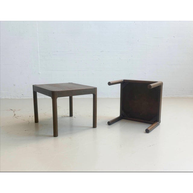 This compact side table from the 1970s is characterized by its minimalist, linear design and dark-stained wood surface....