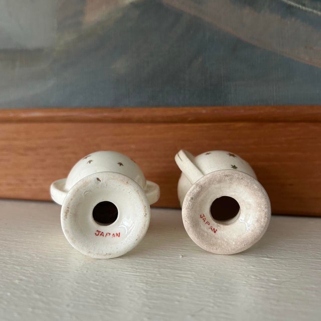 Adorable porcelain cream salt and pepper shakers. Metallic gold star details. Marked Japan on the bottom. Urn shape. Not...