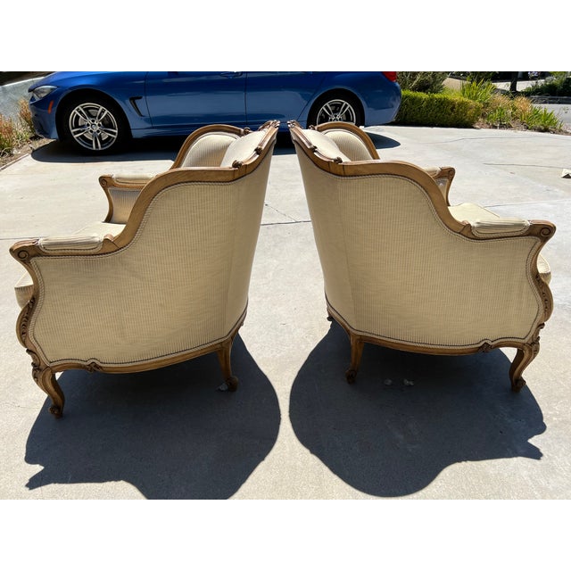 A pair of antique French Bergére Chairs in Louis XV style from the early 20th Century. These pretty armchairs are inspired...