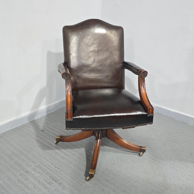 Fine quality brown leather and mahogany swivel office desk chair, standing on brass castors, brass studded and in...