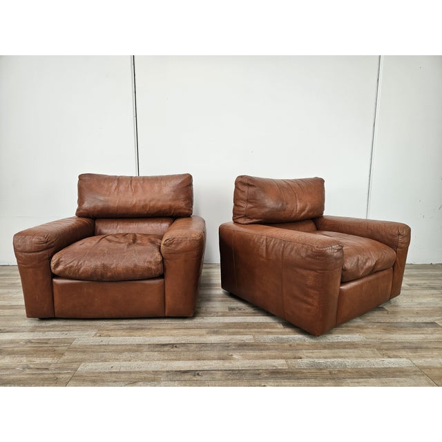 An elegant pair of brown leather armchairs dating back to the 1980s. One of them bears the Moroso label with the Osaka...