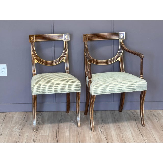 A set of eight faux rosewood dining chairs in the Regency style, each with a curved back featuring a shaped horizontal...