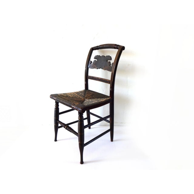 An early Hitchcock chair with a Cornucopia splat and pillow back. Rush seat. Turned legs. Black lacquer with faded...