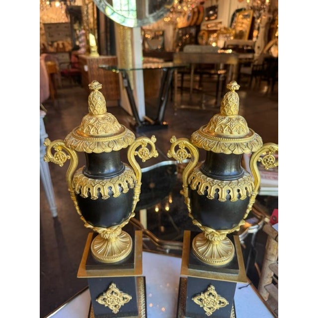 The pair of 19th c. French bronze urns is a set of decorative collectibles that holds historical significance and adds an...