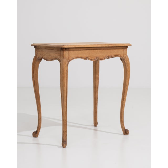 A French side table in oak designed in the Louis XV style, dating to the early 20th century. The form is defined by curved...