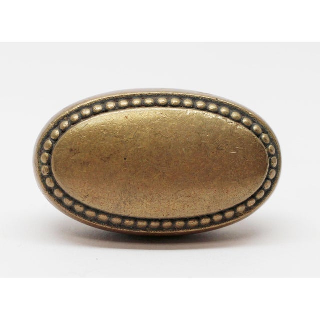 Doorknob with a beaded trim and a plain center made of brass in an antique finish. The manufacturer and date of creation...
