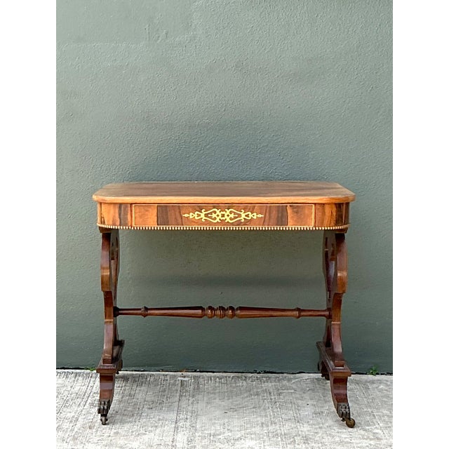 This vintage side table pairs richly grained wood with intricate brass inlay along its edges and center, striking an...