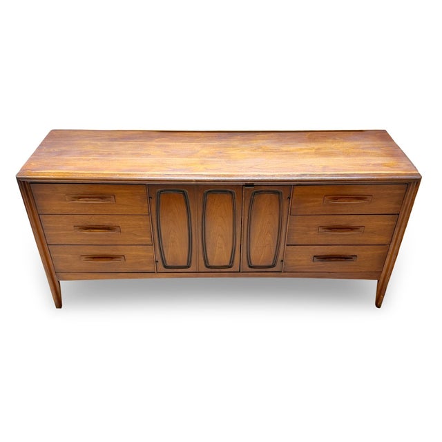 1960s mid-century modern Broyhill Emphasis nine-drawer walnut dresser with sculpted pulls. The three center drawers are...