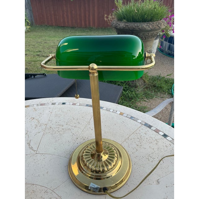 Vintage classic banker’s lamp features the iconic emerald‑green glass shade paired with a round brass‑tone metal base and...