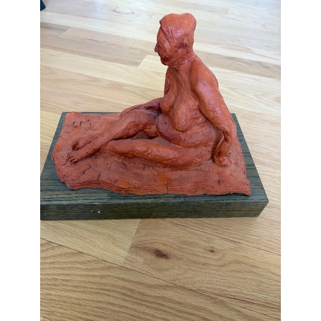 A compelling and tactile original sculpture depicting a seated female figure. This piece features a rich, earthy...