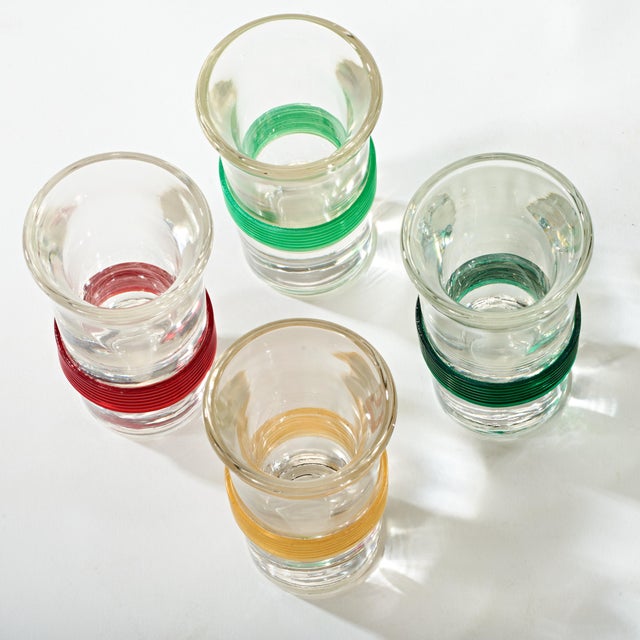Clear shot glasses with colored bands of rubber. 1 - red, 1 - yellow, 1 - light green, and 1 - dark green.