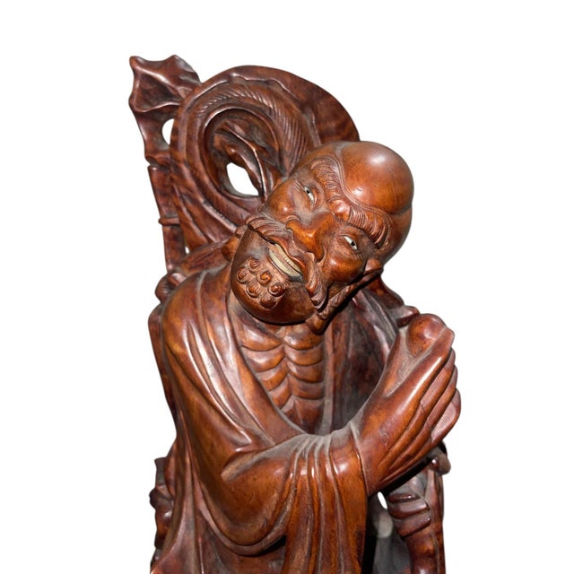 A finely carved Late Qing Dynasty (Late 19th Century) Chinese rosewood figure depicting a Luohan (Arhat), accompanied at...