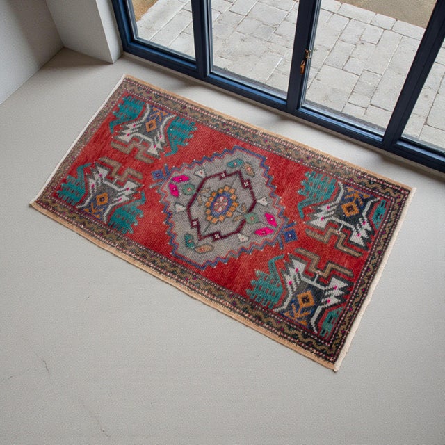 A bold terracotta-red ground gives this small Turkish rug instant warmth, while the cool gray medallion keeps the look...