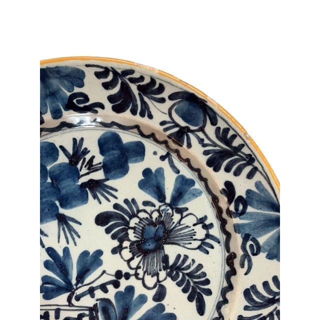 A beautiful 18th century Delft plate featuring “Garden” motif, hand-painted in rich cobalt blue. Rim exhibits natural wear...