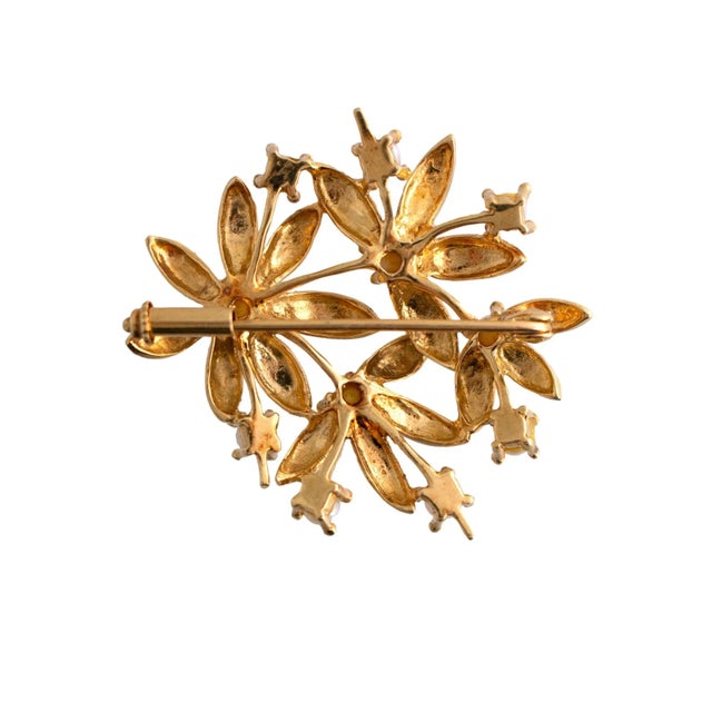 This brooch is crafted in 18k yellow gold. The piece features a floral design with intricate leaf patterns. Accented with...