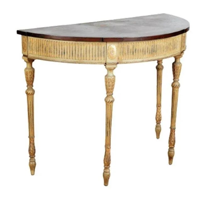 A carved wood and painted Adam style demi lune console table with foliate motif inlaid top, fluted and gilt apron and...