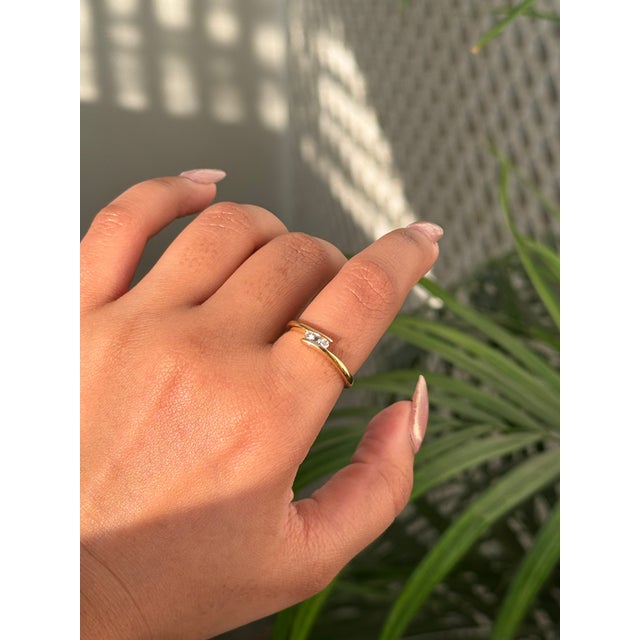 This minimalist bypass ring features a 0.03 carat three round diamonds, set in 18k yellow gold. This sleek open design,...