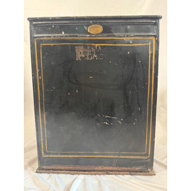 This is an antique English coal bin in black japanned tole (painted tin), with a scalloped, curved top edge and a straight...