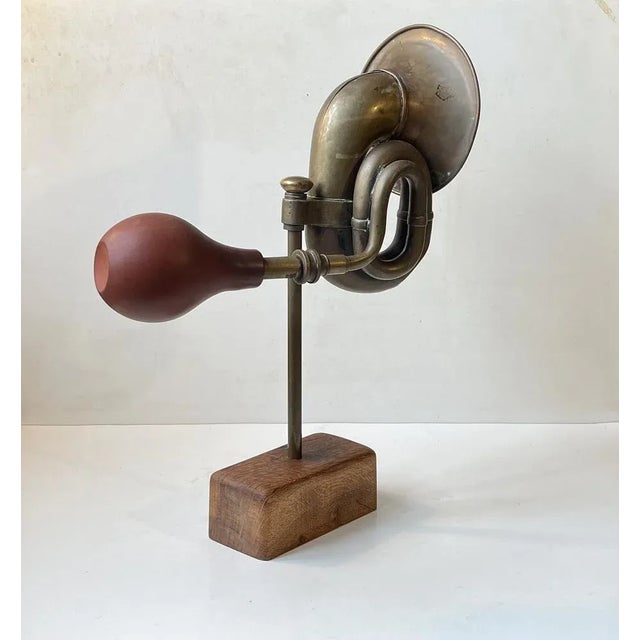 Unusual mounted object in the shape of a antique/1920s brass vehicle horn set on a brass rod and a patinated oak...