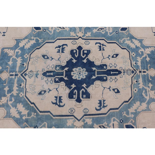 This unique vintage Oushak from Turkey displays cream/ivory background with variety of blue colors on a medallion design....