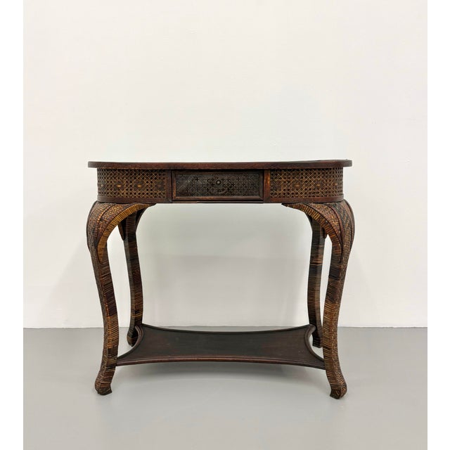 An elegant vintage writing desk showcasing finely woven rattan craftsmanship with a warm, richly patinated finish. The...