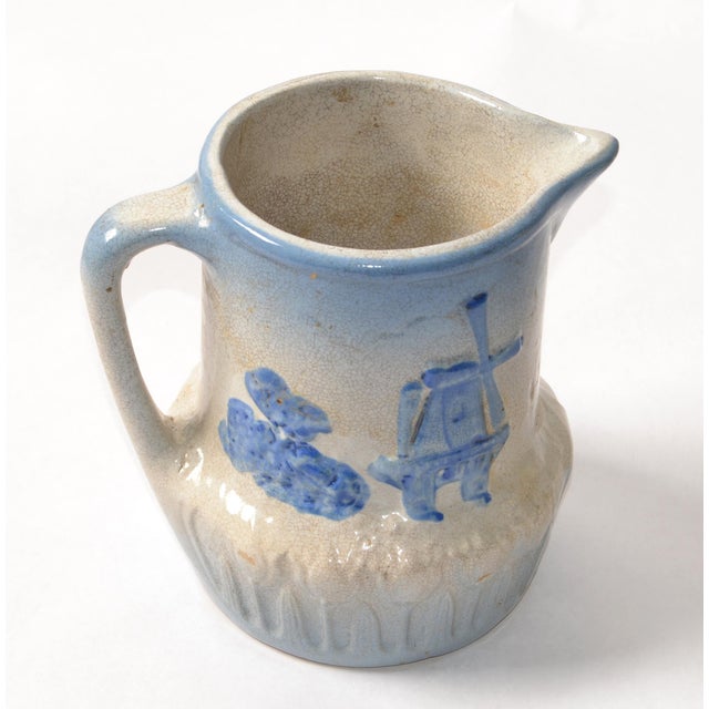 Early 20th Century vintage blue and beige stoneware, earthenware pitcher decorated with a Dutch windmill and tulip motif....