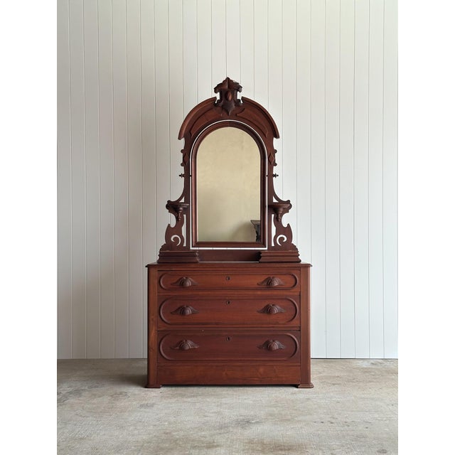 This antique walnut dresser features a tall architectural mirror with a molded arched frame, pierced side brackets, carved...