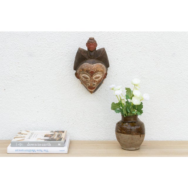 Discover the captivating allure of authentic African art with this vintage hand-carved wooden mask. Imbued with a rich...