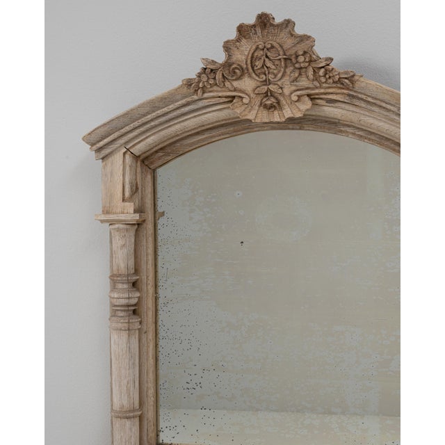 This 1900s French Louis XVI carved oak mirror with shelf features an elegant architectural silhouette and refined...