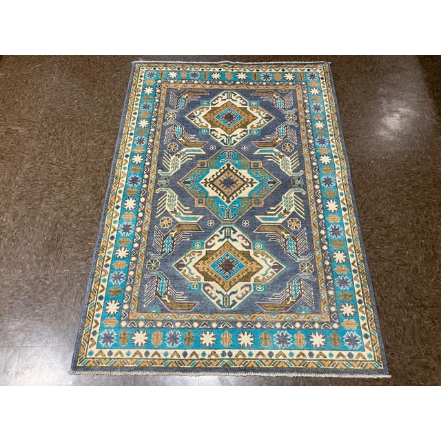Hand-knotted Pakistani Kazak wool rug featuring a blue-gray field with three geometric medallions arranged vertically. The...