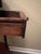 Vintage three-tier round accent table featuring turned spindle legs, a pull-out storage drawer, and raised gallery rails...