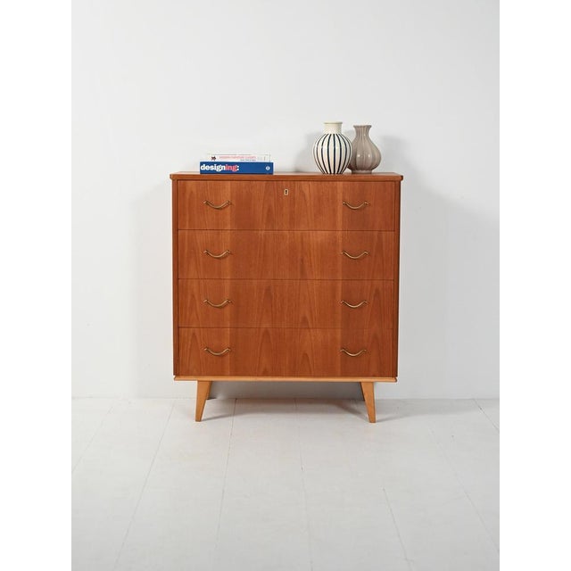 Scandinavian teak chest of drawers from the 1950s with four drawers, brass handles, and a contrasting oak base, for a...