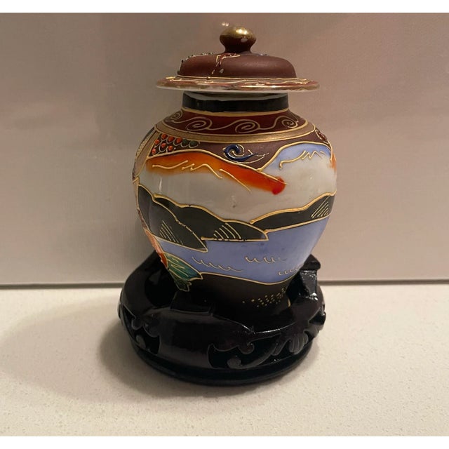 This is a small decorative hand-painted Satsuma Ginger Jar with lid, on a wooden base. The size is miniature....