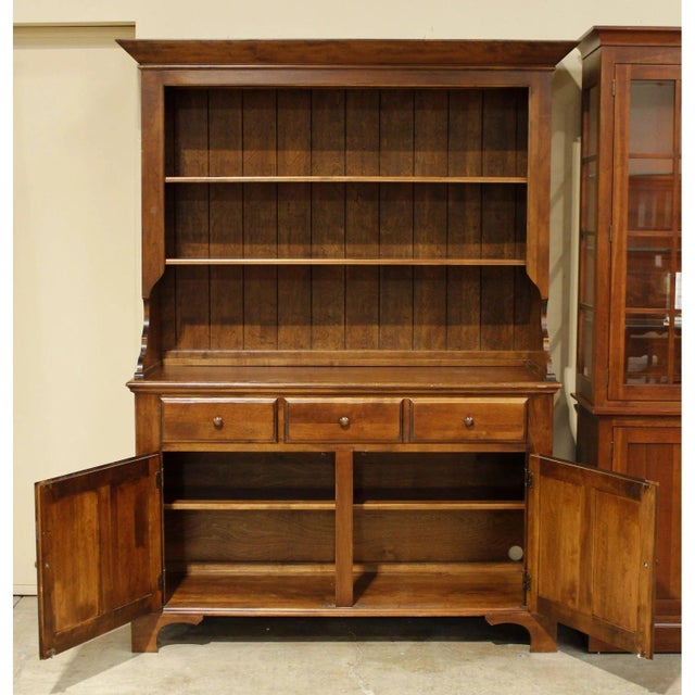 Crafted in a traditional style, this piece features a warm wood finish, paneled cabinet doors, and a substantial crown-...