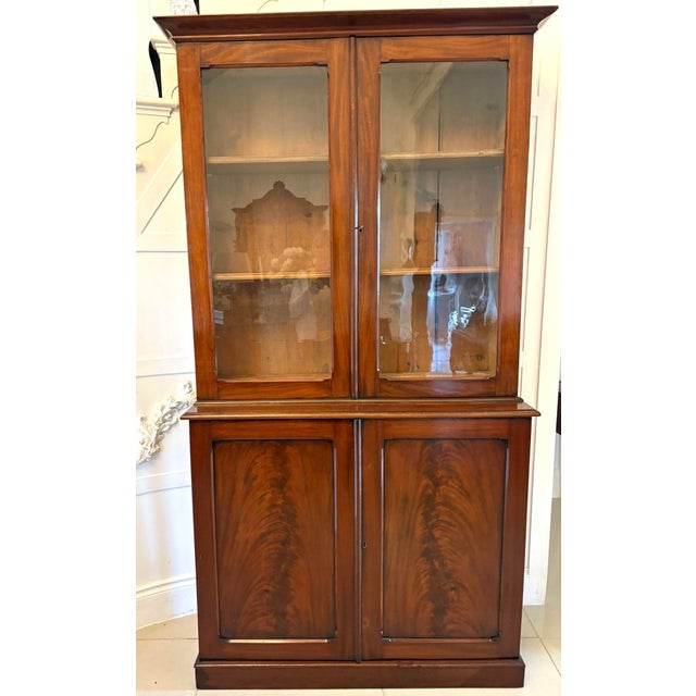 Antique Victorian quality figured mahogany bookcase having a shaped cornice above a pair of mahogany glazed doors opening...