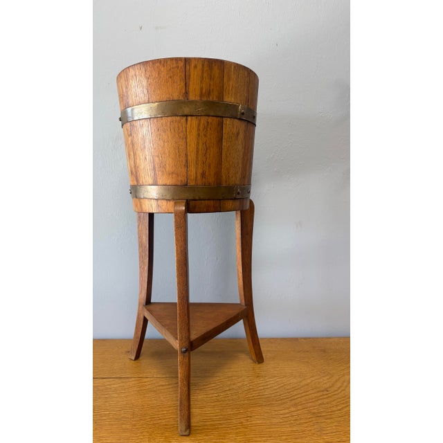 This early 20th century English oak coopered plant stand, crafted in the manner of R.H. Lister, is a quietly elegant...