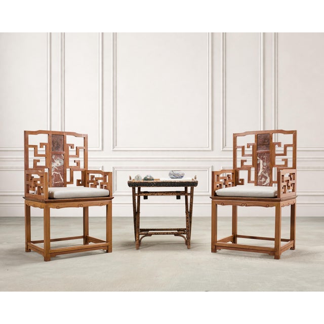 An organic and elaborately crafted pair of 20th century Chinese Export hardwood scholar's armchairs crafted in the Ming...