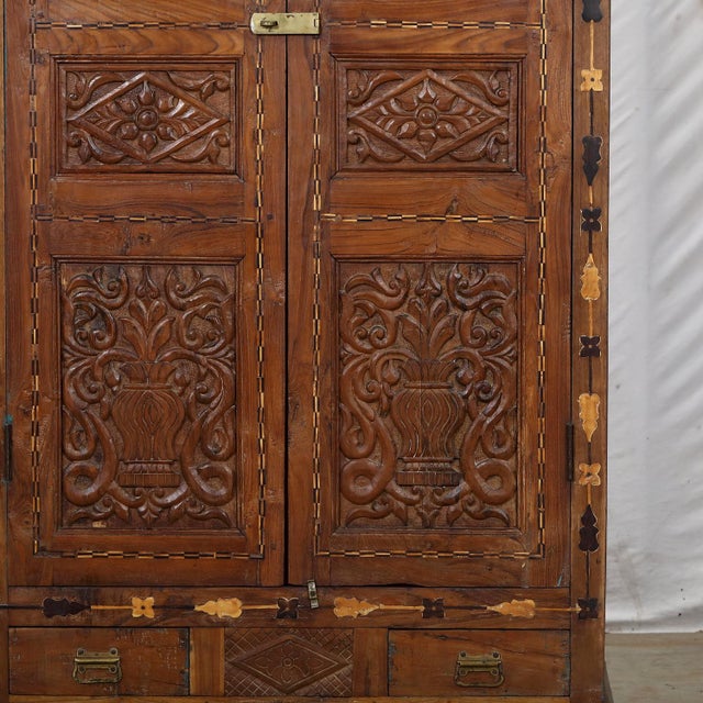 Antique Indian Carved Teakwood, Marquetry, and Painted on Glass Panels Armoire, c. 1900-30. In richly patinated teak, with...