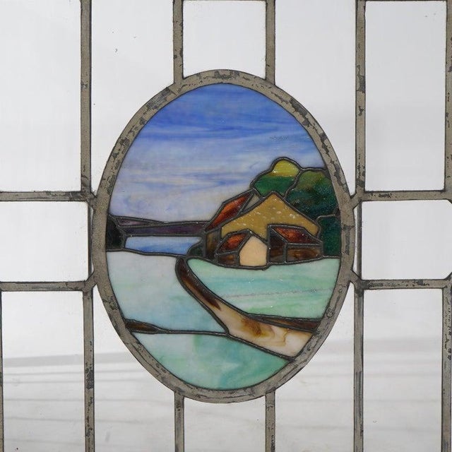 An antique Arts & Crafts window offers leaded glass construction with colorless panels surrounding central reserve with...