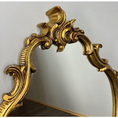 This Vintage French wall mirror presents an elegant shaped silhouette with richly sculpted scrollwork and flowing...