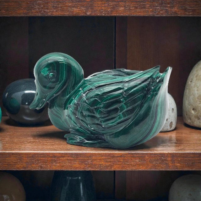 This hand-carved duck figurine is crafted from natural banded malachite, displaying the concentric veining characteristic...