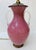 Vintage Chapman table lamp with a rich pink glass body, clear loop handles, and dark brass-tone mounts. The rounded urn...