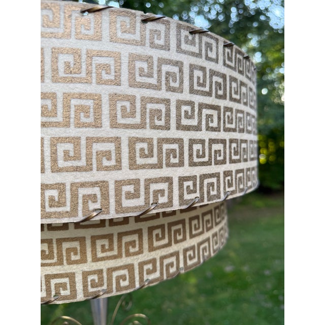 Offering a pair of two-tier fiberglass lampshades in a Greek Key pattern, circa 1950 Gilt Greek key against a beige...